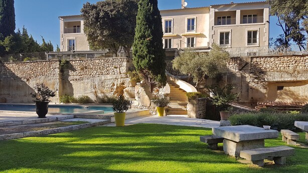 A villa with a stone wall, a swimming pool, and a well-maintained garden. - Hôtel Belesso (Fontvieille)