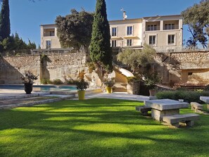 Una villa con muro de piedra, piscina y un jardín bien cuidado.