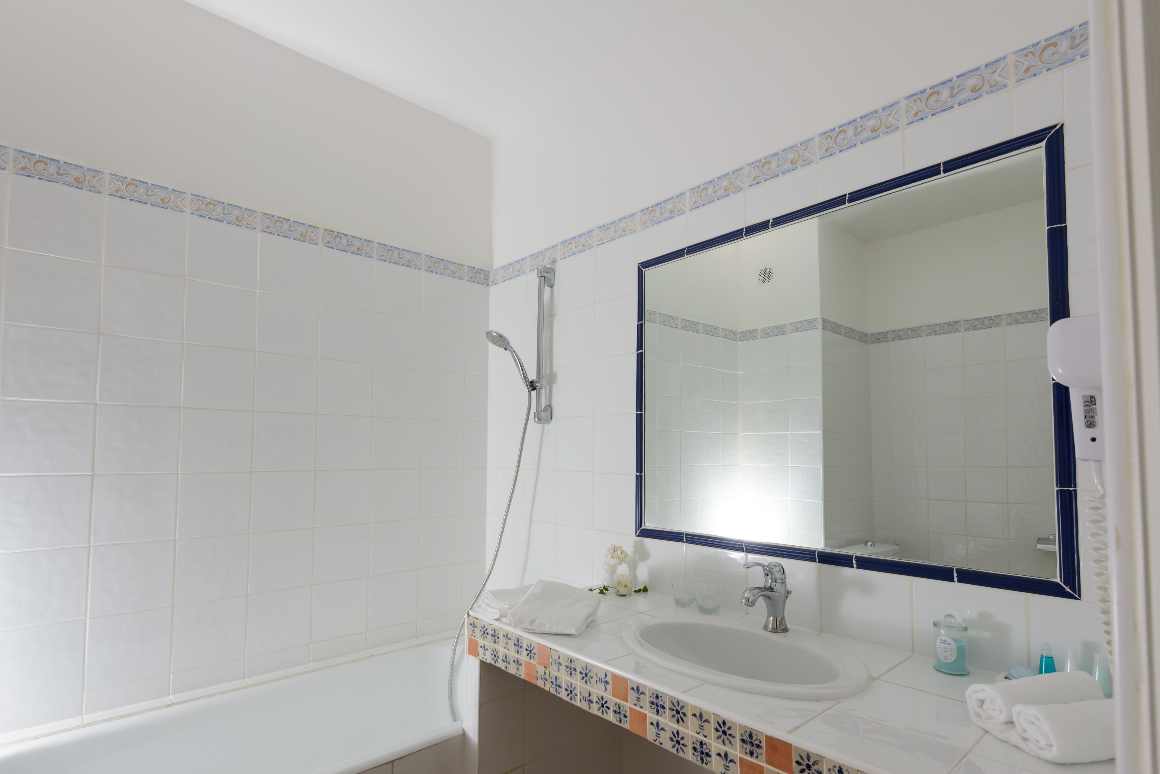 Ein Badezimmer mit einem weißen Waschbecken, einem großen Spiegel und einer Dusche.
