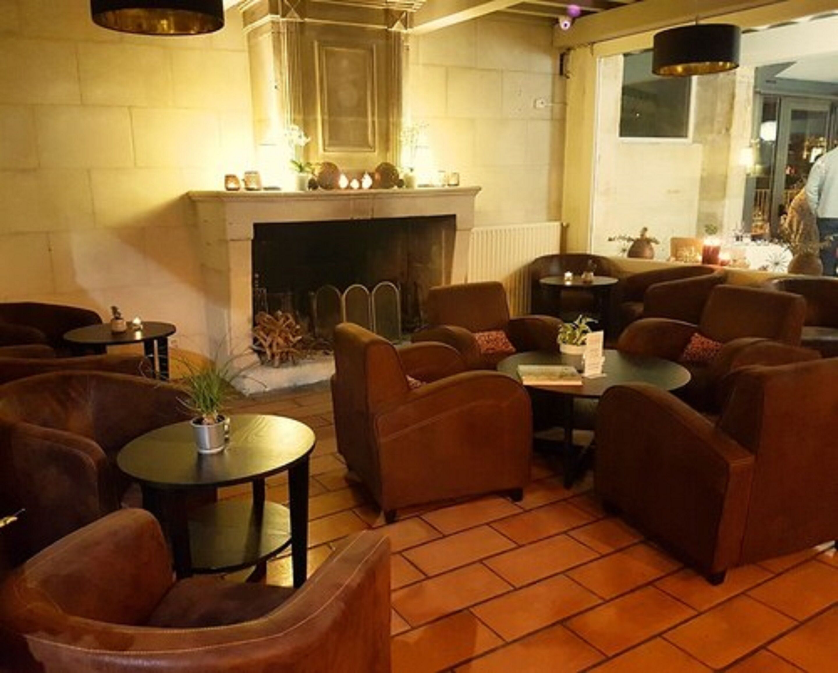 Una sala de estar acogedora con varios sofás y mesas, una chimenea y suelo de baldosas.