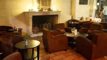 Una sala de estar acogedora con varios sofás y mesas, una chimenea y suelo de baldosas.