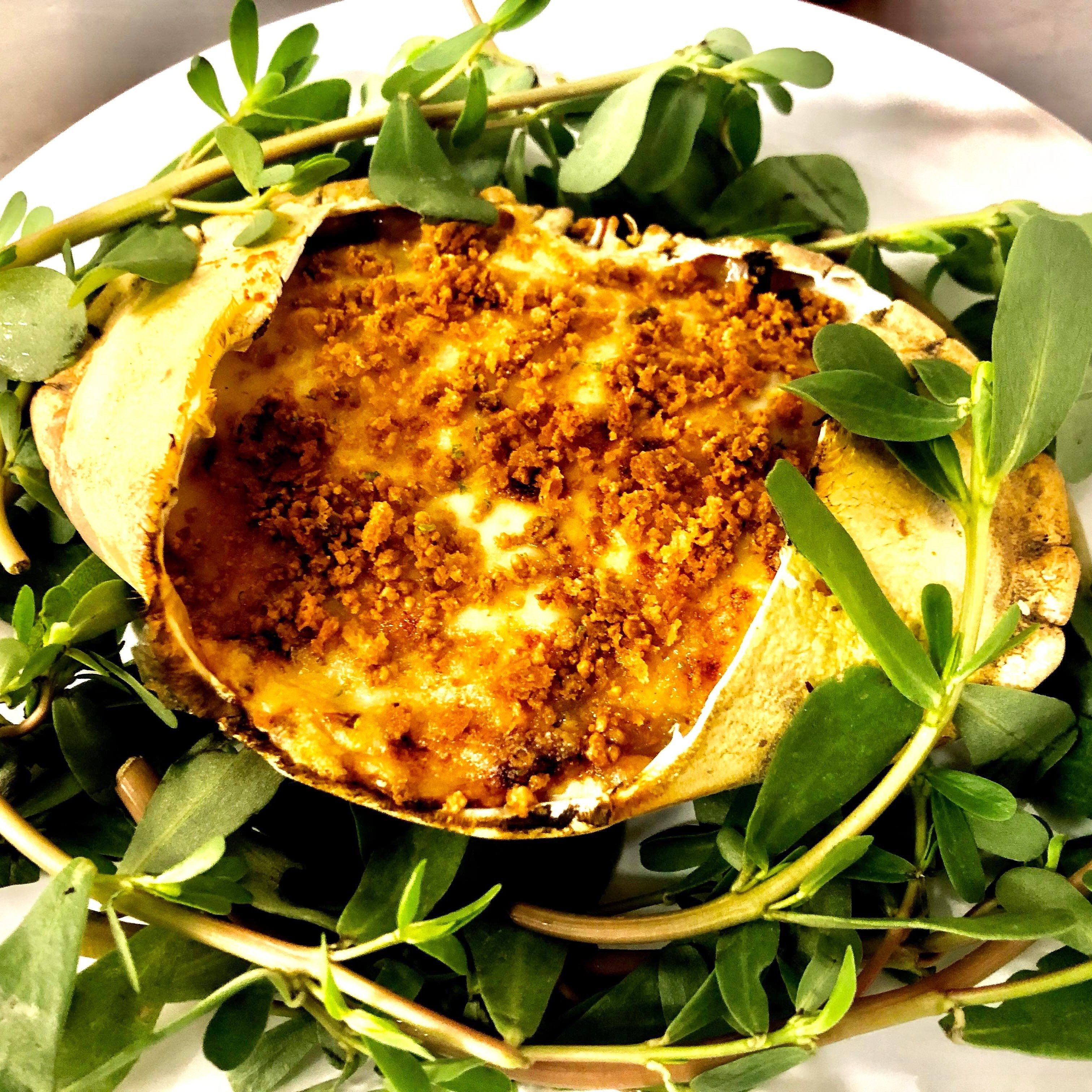 Un plato con una cobertura crujiente, rodeado de hojas verdes.