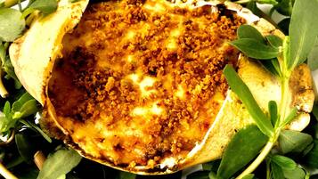 Un plato con una cobertura crujiente, rodeado de hojas verdes.