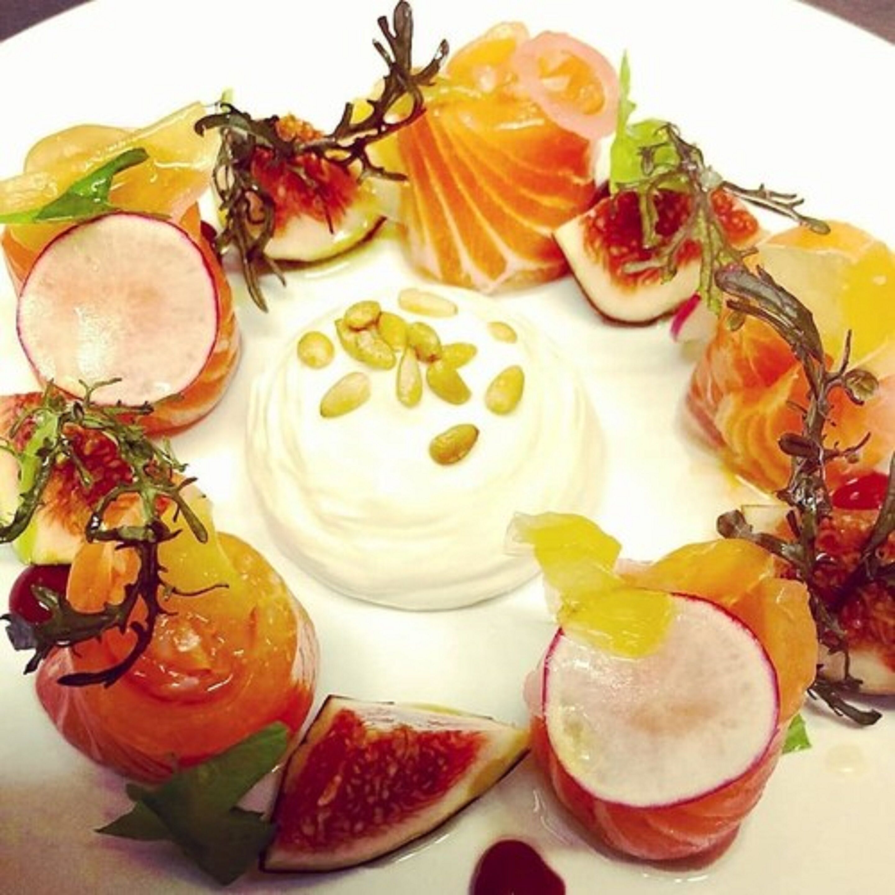 A plate of food with various fruits and a central dollop of cream.