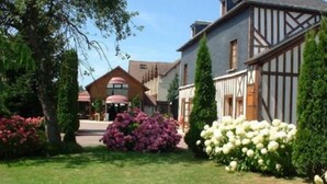 Een traditioneel vakwerkhuis met een verzorgde tuin vol roze en witte bloemen.