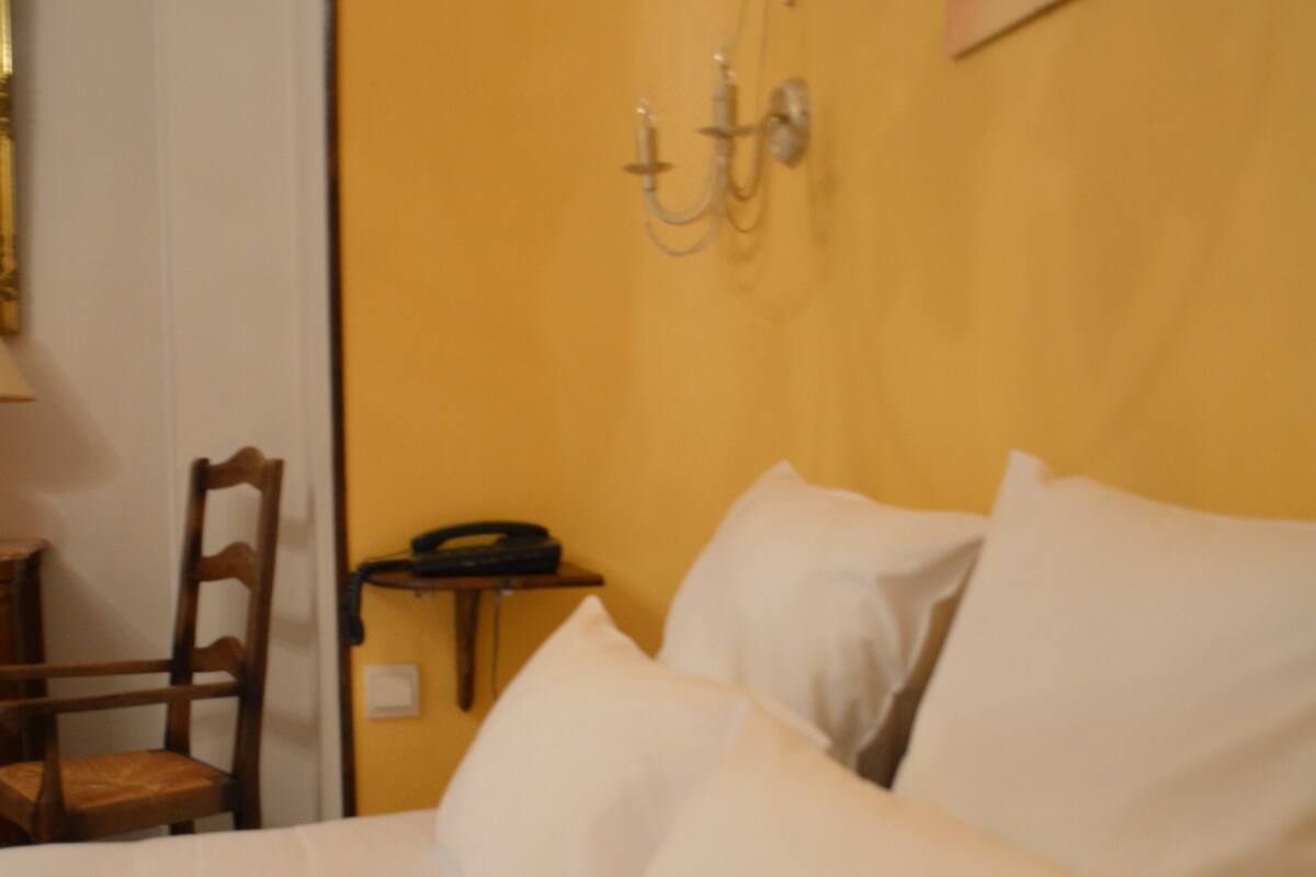 Ein Hotelzimmer mit Bett, Stuhl, Nachttisch und Wandlampe.