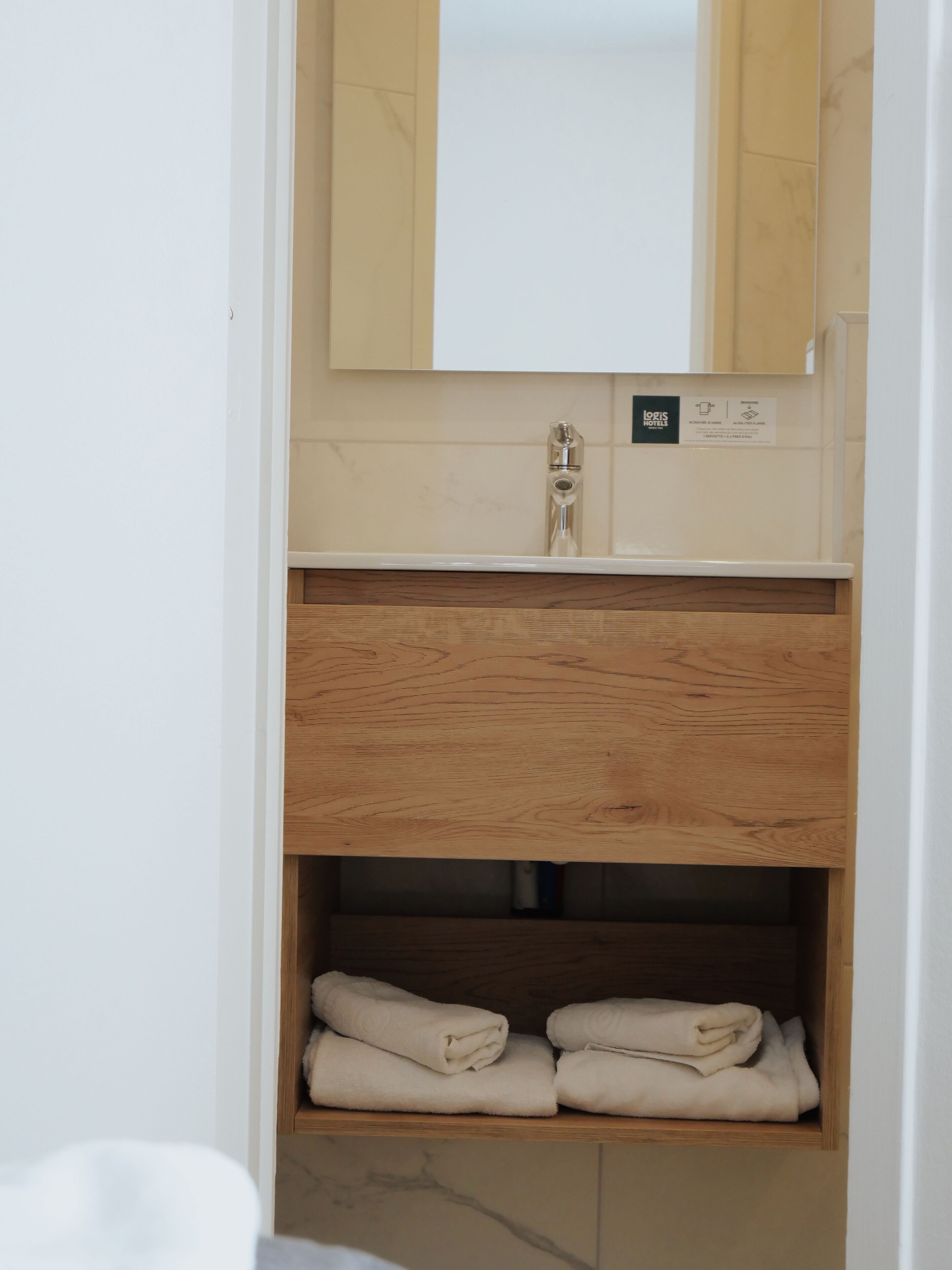 Ein Badezimmer mit Spiegel, Waschbecken und einem Holzboden mit Handtüchern.