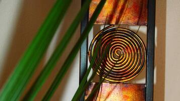 Une œuvre d’art murale dotée d’un motif en spirale métallique, d’une base sphérique et d’un panneau texturé.