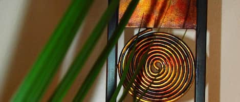 A wall-mounted artwork with a metallic spiral design, a spherical base, and a textured panel.