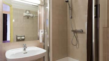 Une salle de bain équipée d’un lavabo, d’un miroir, d’une douche et d’un porte-serviettes.