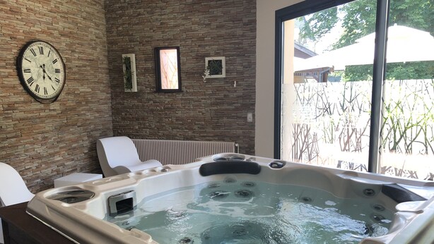 A spa area with a hot tub, a clock, and framed pictures on a stone wall.