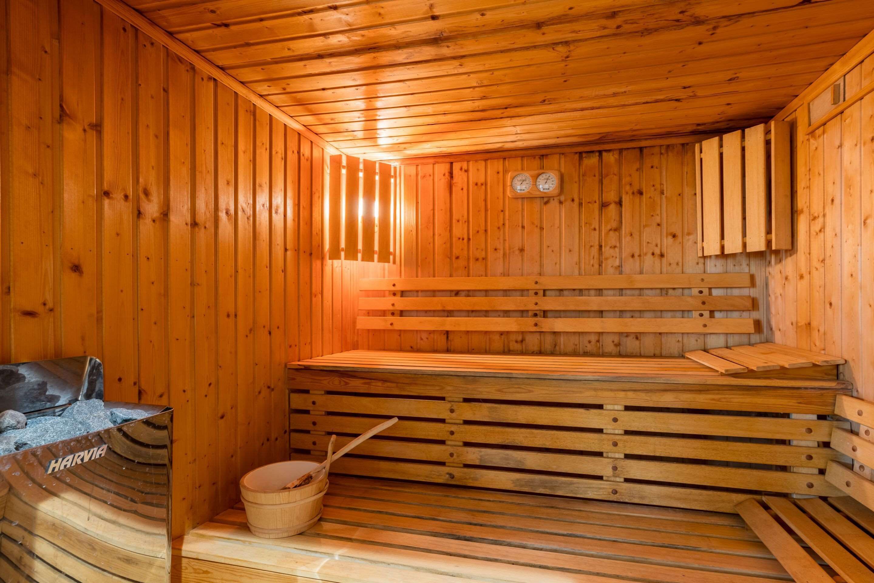 A wooden sauna with benches and a wooden bucket.