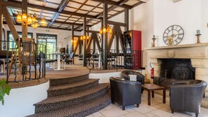 A spacious lobby with a fireplace, a staircase, and a seating area with leather chairs.