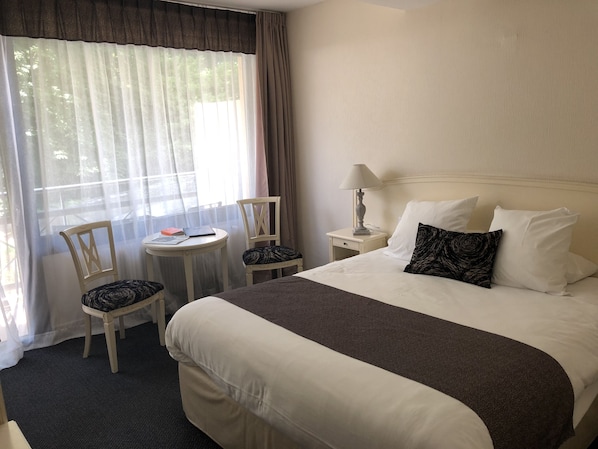 A hotel room with a large bed, two chairs, a small table, and a lamp. - Le Moulin du Landion Hôtel & Spa (Dolancourt)