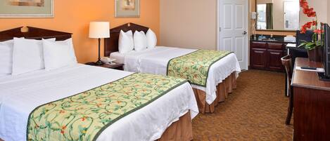 Ein Hotelzimmer mit zwei Betten, einem Schreibtisch, einem Stuhl, einem Spiegel und einer Badezimmertür.