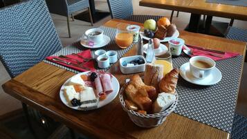 A breakfast table with various food items, including pastries, fruits, and beverages.