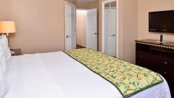 A hotel room with a bed, a TV, a dresser, and a lamp.