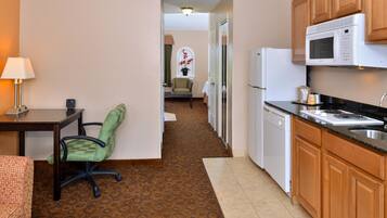 A compact kitchen with a microwave, refrigerator, and a small dining area with a table and chairs.