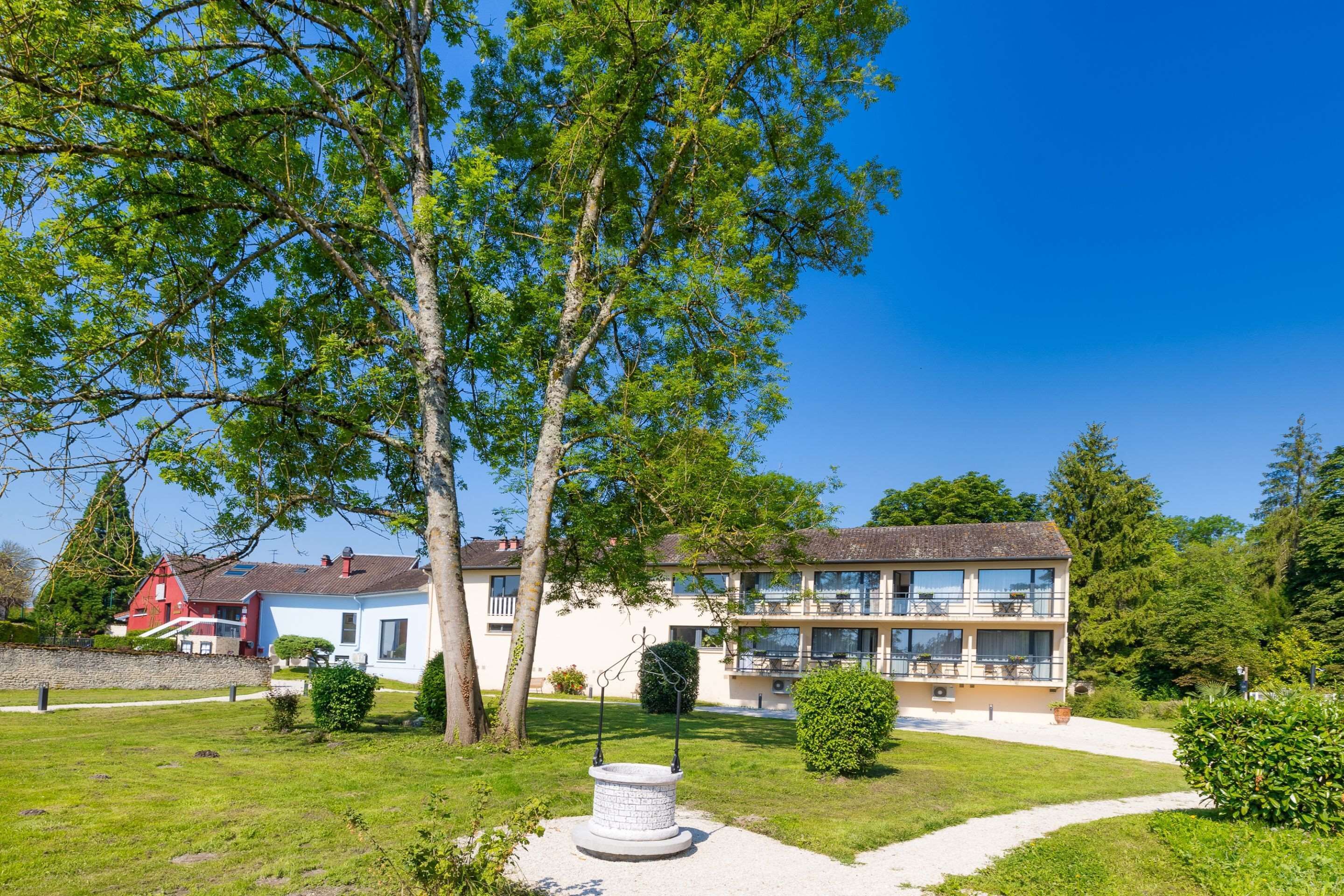 A two-story building with a balcony, surrounded by well-maintained lawns and trees.