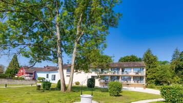 A two-story building with a balcony, surrounded by well-maintained lawns and trees.