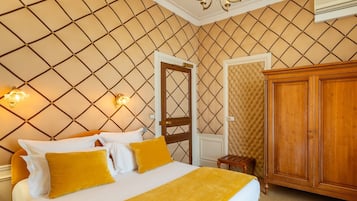 A bedroom with a bed, a wardrobe, a door, and a chandelier.