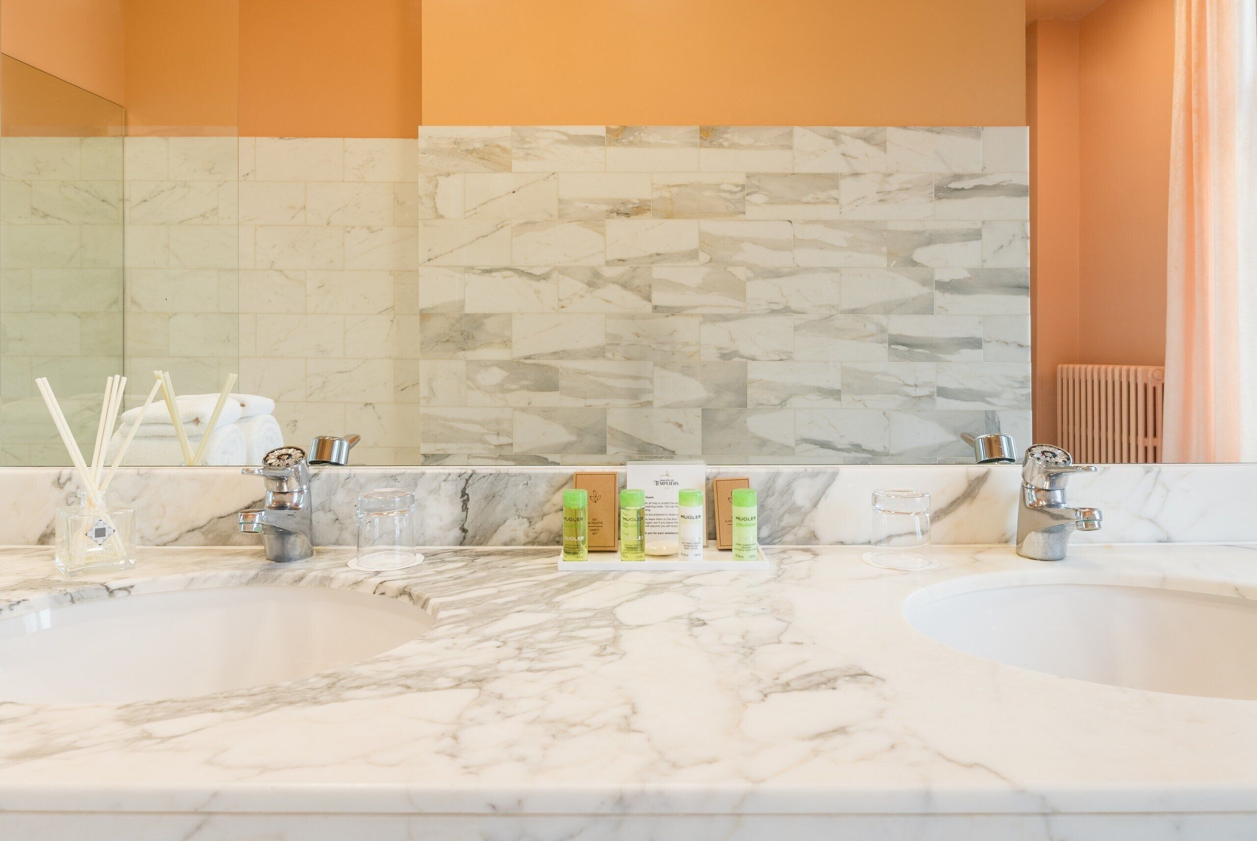 Un bagno con due lavandini, piani in marmo e un grande specchio.