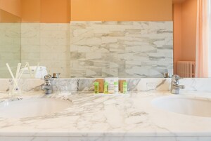 Un bagno con due lavandini, piani in marmo e un grande specchio.
