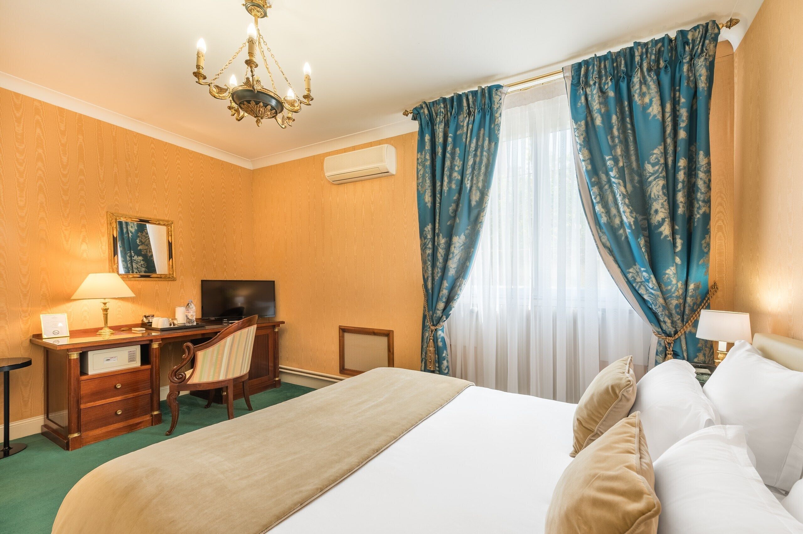 Habitació d'hotel amb un llit, escriptori amb una cadira, televisió i un candelabrum.