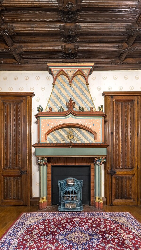 A room with a fireplace, wooden paneling, and a patterned carpet.