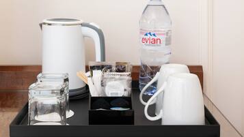 Una bandeja con tetera, botella de agua, vasos y taza.