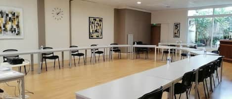 Un salón de conferencias con una larga mesa, sillas y obras de arte en las paredes.