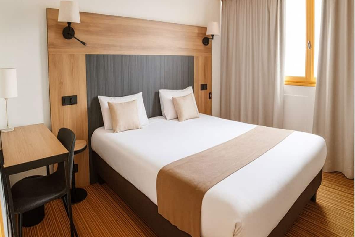 A hotel room with a large bed, a desk, and two chairs.