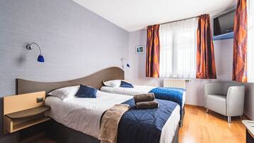 A hotel room with two beds, a TV, a desk, and a chair.