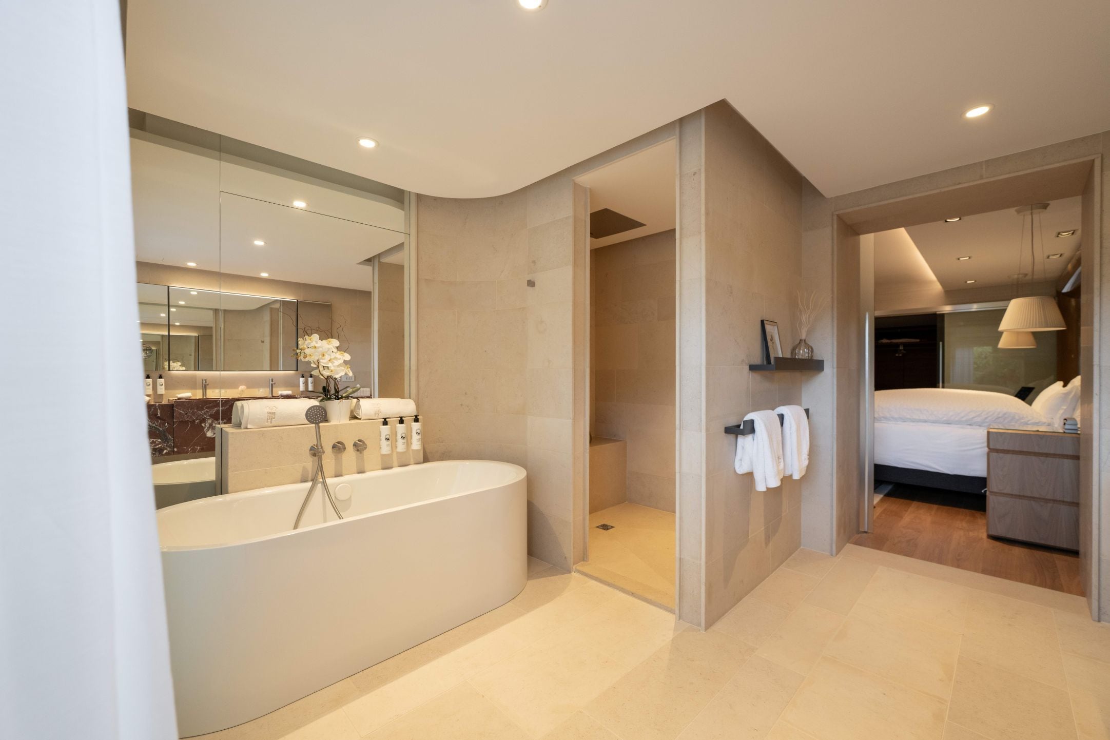 A modern bathroom with a freestanding bathtub, a large mirror, and a shower area.