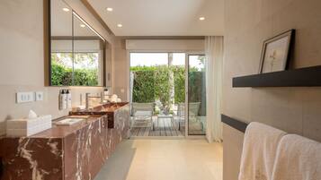 A modern bathroom with a marble vanity, a large mirror, and a glass door leading to a patio with outdoor furniture.