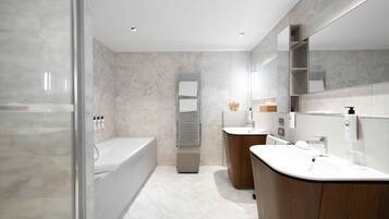 Une salle de bain moderne dotée d’une douche à parois de verre, d’une baignoire sur pieds et d’un meuble-lavabo avec miroir.