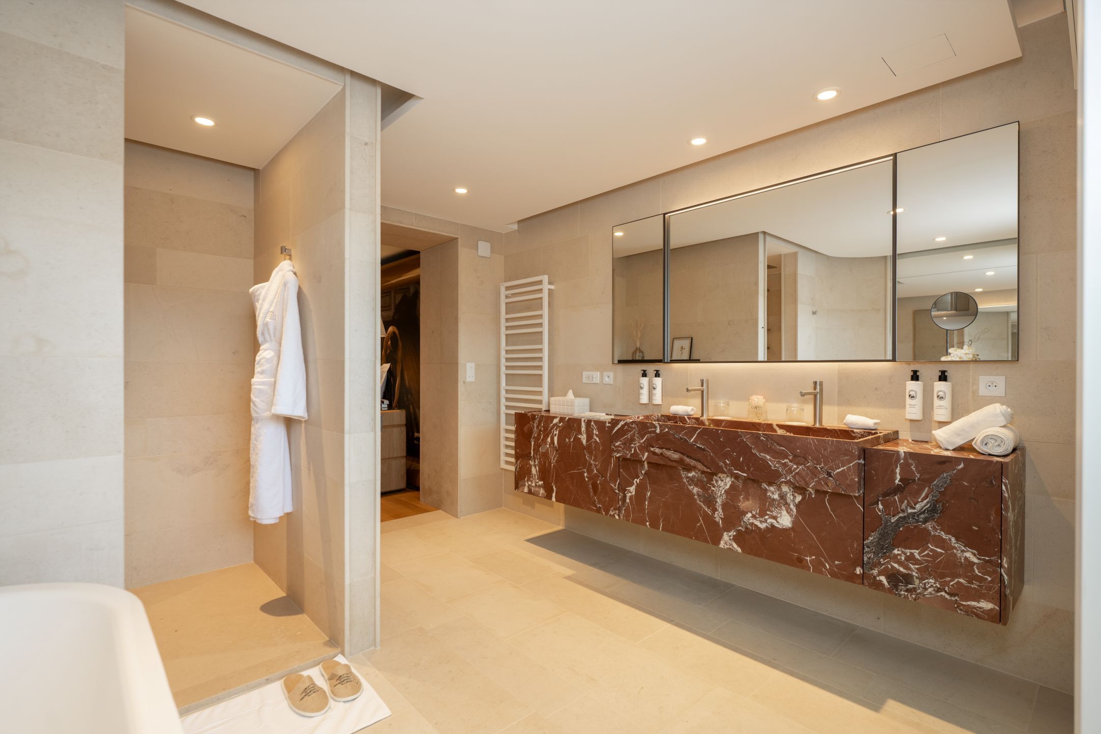 A modern bathroom with a marble vanity, a large mirror, and a walk-in shower.