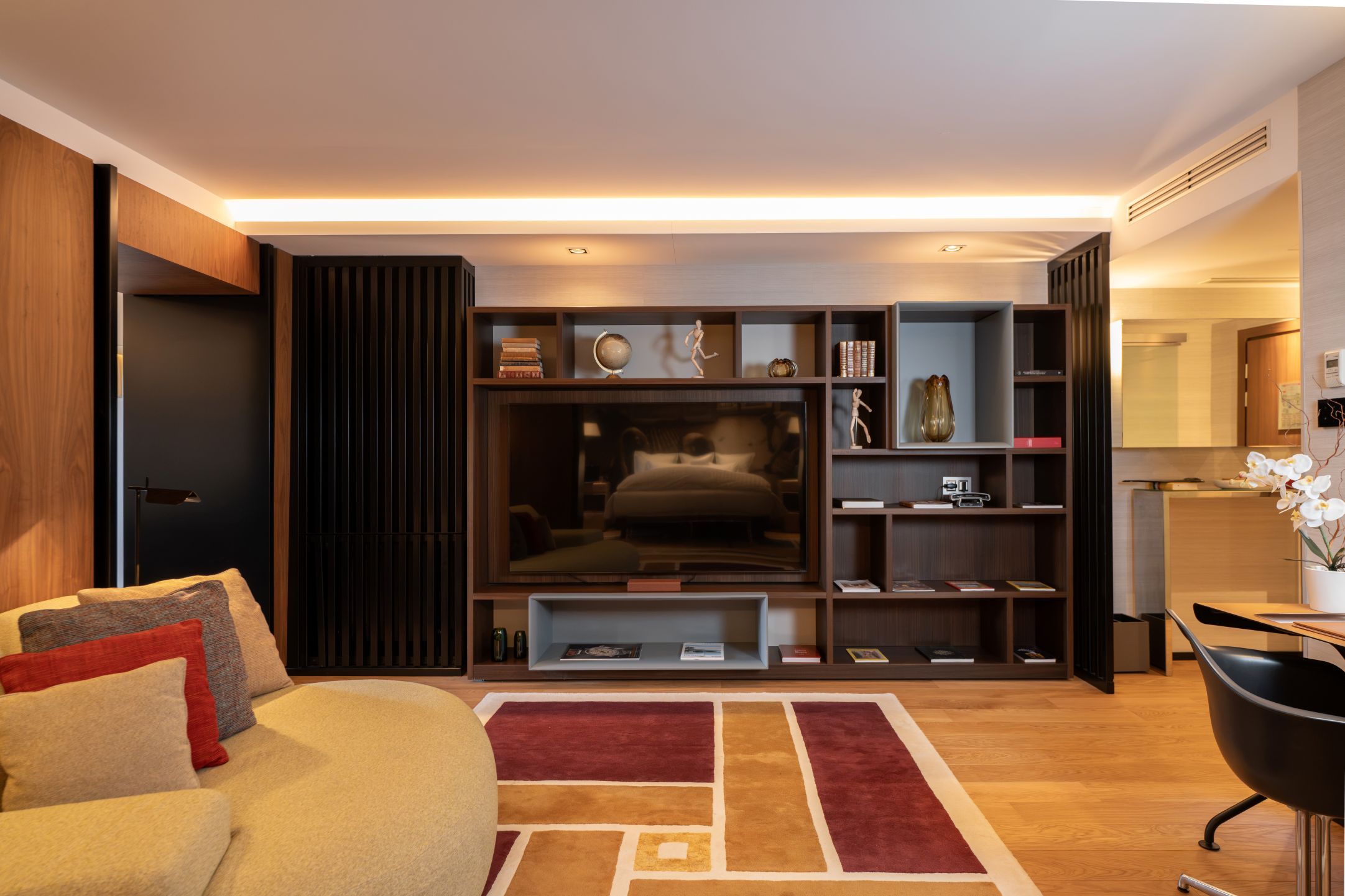 A modern living room with a sofa, a coffee table, a TV, and a bookshelf.