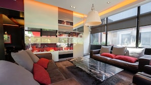 A modern living room with a sectional sofa, a glass coffee table, and a large window offering a city view.