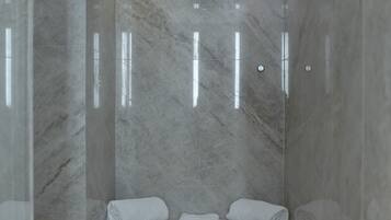Experience a luxurious shower in a sleek, minimalist space with a polished marble finish and ample lighting.