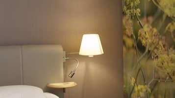 Una habitación de hotel con cama, lámpara de noche y un mural floral en la pared.