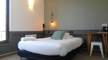 Una habitación de hotel con cama, mesita de noche y escritorio con silla.