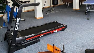 A gym with a treadmill, a stationary bike, a punching bag, and a table tennis table.