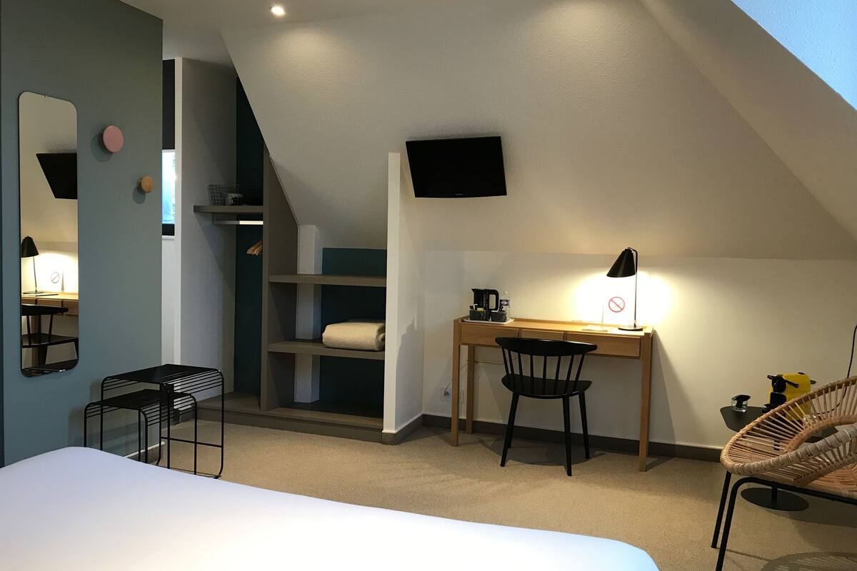 Een slaapkamer met een bed, een bureau, een stoel, een televisie en een plank.