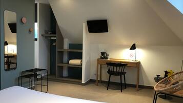 A bedroom with a bed, a desk, a chair, a TV, and a shelf.