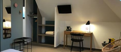 A bedroom with a bed, a desk, a chair, a TV, and a shelf.