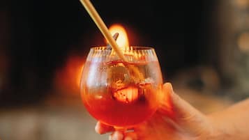 Een hand die een cocktailglas vasthoudt met een brandende kaars erin.