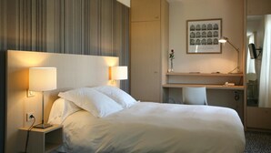 A hotel room with a large bed, two bedside lamps, a desk with a chair, a mirror, and a framed picture on the wall. - Hotel Ar Milin (Chateaubourg)
