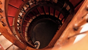 A spiral staircase with wooden railings and a red carpeted wall. - Hotel de la Vallee (Dinard)