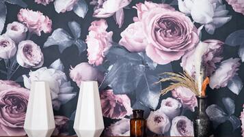 Una repisa con tres jarrones sobre un fondo de papel tapiz floral.